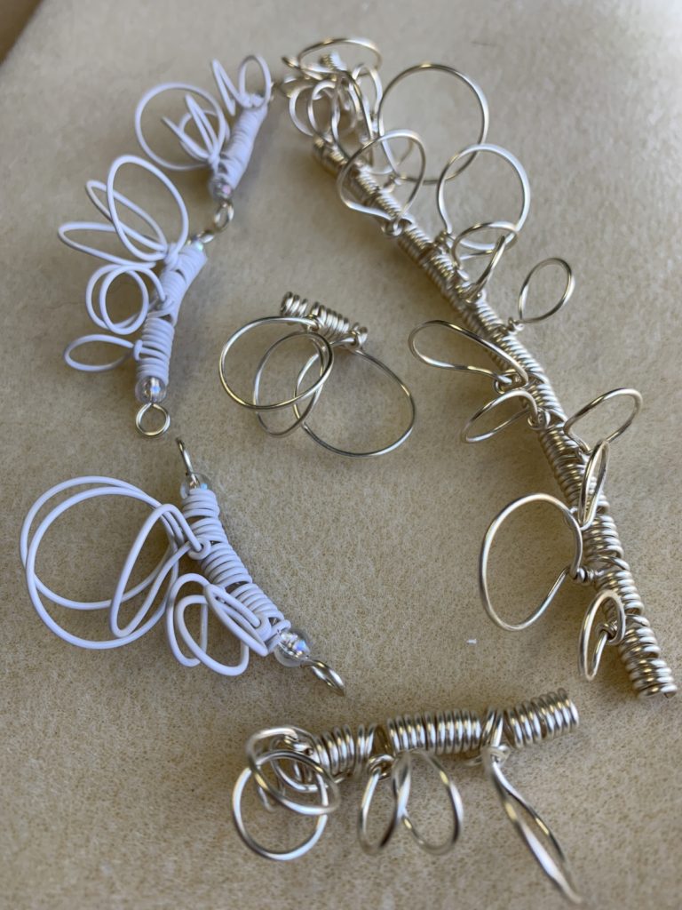 Disconnected sections of looping wire in white and silver that will be joined into a necklace
